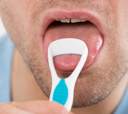 Close-up of mid adult man cleaning his tongue with scraper