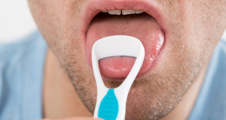 Close-up of mid adult man cleaning his tongue with scraper