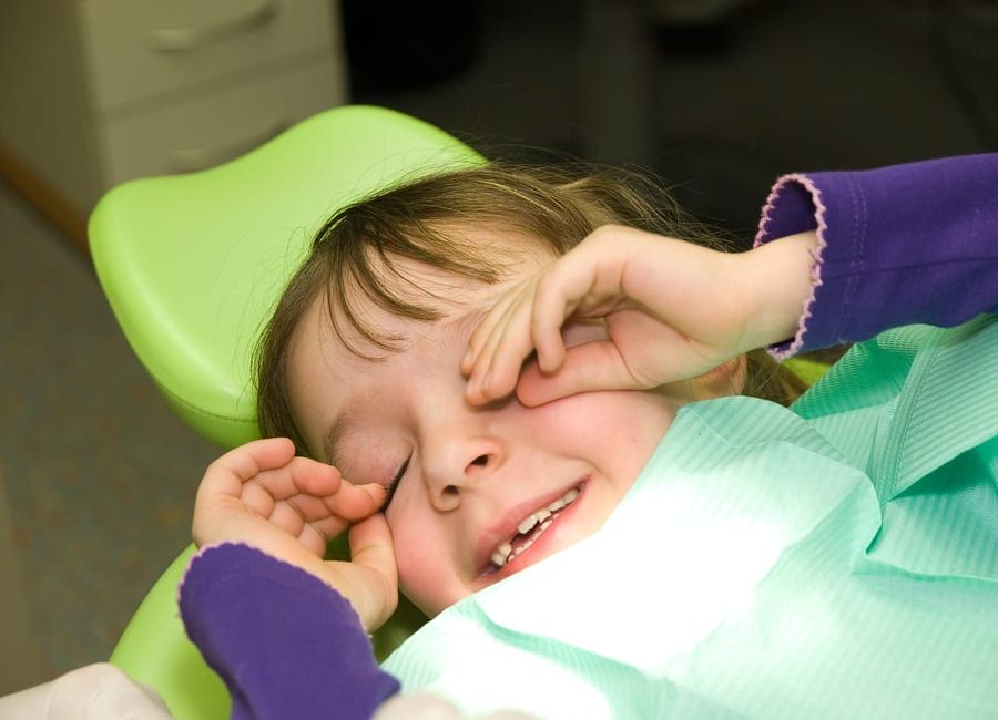 Little girl rubbing her eyes after the dental surgery while under anesthesia