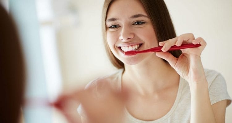 Woman Brushing Her Teeth at Mirror