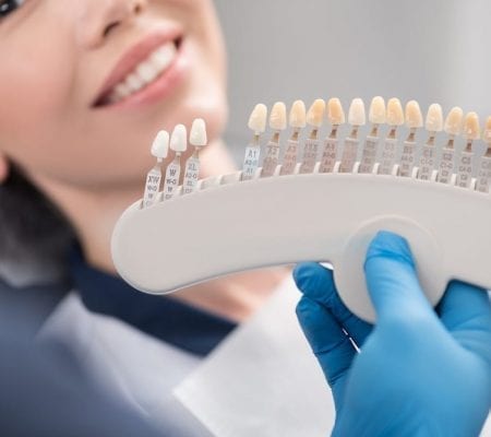 Orthodontist arms showing teeth implants to patient.